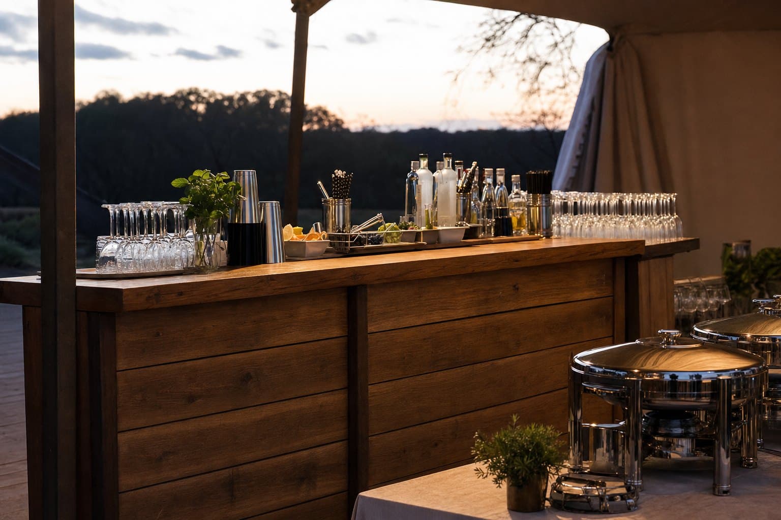 Portable event bar and stainless catering chafing dishes set up under a tent by Creative Events & Rentals